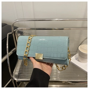 Détail du sac bleu clair à motif crocodile avec chaîne dorée et boucle carrée en métal