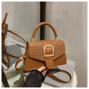 Détail d'un petit sac à main marron tressé avec boucle fer à cheval dorée et bandoulière