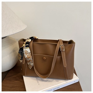 Détail d'un sac cabas marron en similicuir avec foulard décoratif sur une table