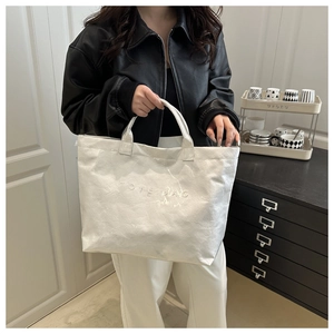 Close-up of white tote bag with embossed letters and unique wrinkled paper texture