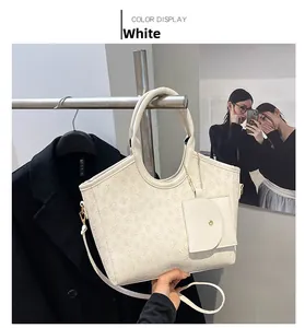 Detailed close-up of white tote bag featuring embossed clover patterns and small purse