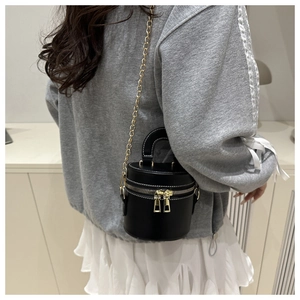 Detailansicht einer schwarzen zylindrischen Mini-Beuteltasche mit goldener Kette