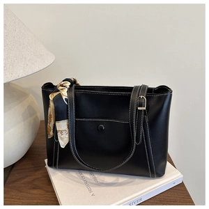 Détail d'un sac cabas en cuir noir avec surpiqûres blanches et foulard en soie imprimé