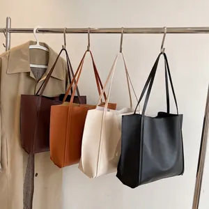 Set of minimalist large capacity faux leather tote bags in four solid colors hanging on a rack