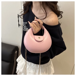 Detailed view of pink crescent handbag with gold round buckle and metallic chain strap