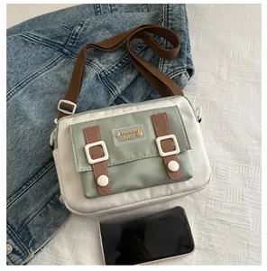 Kleine crossbodytas in wit en muntgroen met telefoon voor maatvergelijking