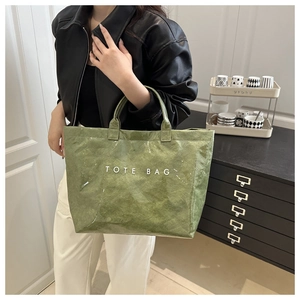 Detail of the glossy grass green tote bag with white TOTE BAG lettering in a home setting