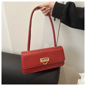 Close-up of red crocodile-embossed leather handbag with gold metal twist lock buckle