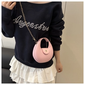 Pink crescent moon bag with gold chain strap carried by a model over blue top