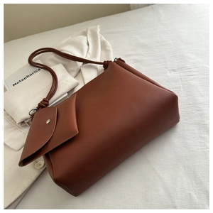 Detail of brown leather bucket bag with knot shoulder strap and detachable mini pouch