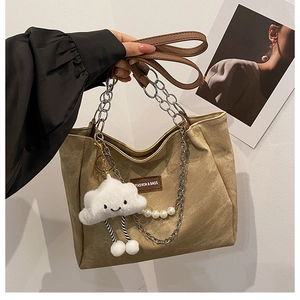 Detail of khaki canvas tote with FASHION leather patch and white cloud plush charm