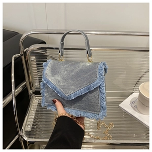 Detail of light blue denim mini bag featuring fringe edges and golden metal chain strap