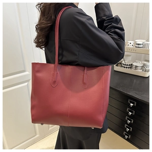 Detailed side view of deep red leather tote bag with sturdy straps and sleek matte finish