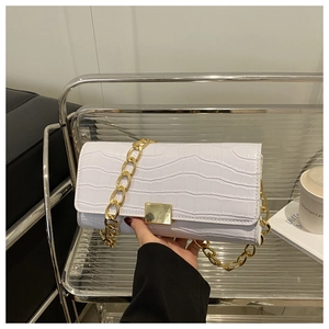 Détail du sac à rabat blanc motif crocodile avec chaîne dorée et boucle métallique