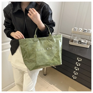 Detail of green tote bag featuring crinkled patent leather texture and white logo lettering