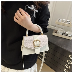 Detail of white leather crossbody bag with woven texture flap and golden square buckle