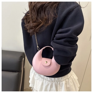 Détail du sac demi-lune rose avec chaîne dorée porté par un mannequin en sweat bleu