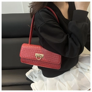 Close-up of red crocodile embossed leather bag with golden metal twist lock on model