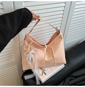 Detailed view of pink nylon tote bag featuring white lace bow and pearl pendant