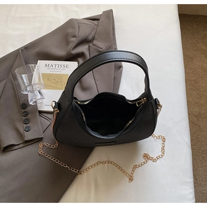 Detail of black dumpling bag featuring woven texture and gold chain strap decoration