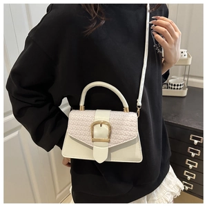 Detail of white square crossbody bag with woven texture and gold buckle on a model
