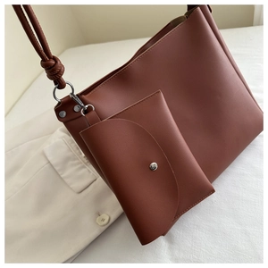 Detail of tan minimalist shoulder bag with matte synthetic leather and mini envelope pouch