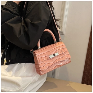 Detail of pink crocodile embossed texture and silver twist lock on stylish shoulder bag