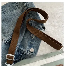 Detail van de verstelbare bruine stoffen schouderband met witte gesp op een casual crossbody tas