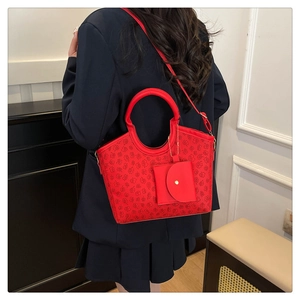 Detail of red floral tote bag featuring round handles and a detachable mini pouch accessory
