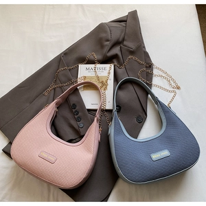 Detail view of pink and blue half-moon bags with woven texture and gold chain straps