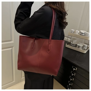 Detail of burgundy large tote bag with matte leather finish and metal bottom studs