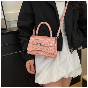 Detailed view of pink croc-embossed handbag featuring a silver twist lock and crossbody strap