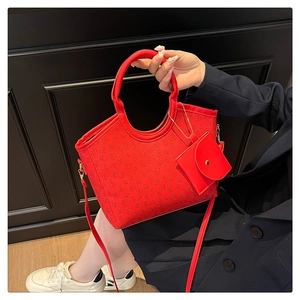 Detailed close-up of red tote bag with four-leaf clover embossing and matching coin purse