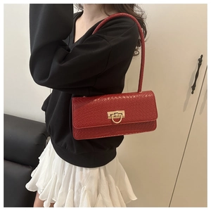 Detail of red woven leather baguette bag with a golden D-ring lock worn on the shoulder