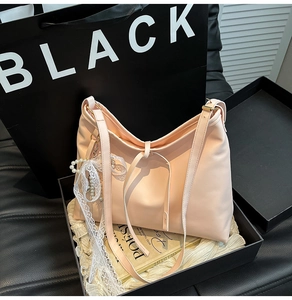 Detail of pink faux leather hobo bag with pearl and lace bow pendant in a black gift box