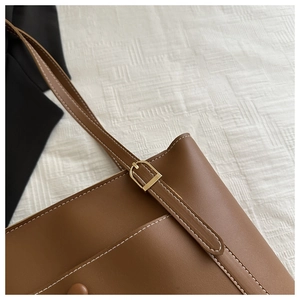 Détail du cabas en cuir PU marron avec surpiqûres blanches et boucles en métal doré
