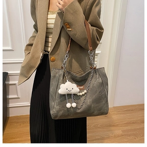 Detail of grey tote bag with brown straps, silver chain, and pearl plush charms