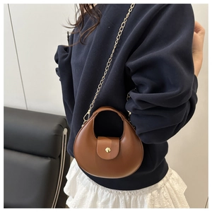 Close-up of brown crescent bag featuring gold metal buckle and elegant chain strap