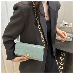 Détail du sac bleu clair à texture crocodile avec chaîne dorée et fermoir métallique