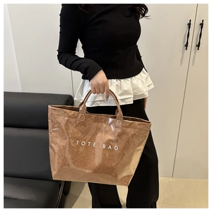 Detail of a brown textured tote bag with white TOTE BAG lettering and short handles