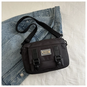 Detail van zwarte nylon crossbodytas met modieus konijn-logo op een platte achtergrond