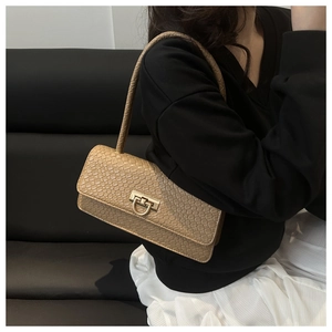 Detail of beige faux crocodile texture underarm bag with gold metal clasp on a model