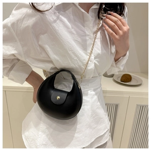 Detail of a black half-moon leather bag with a fine gold chain strap and metal clasp