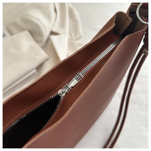 Detail of premium brown bucket bag featuring high-quality silver zipper and leather texture