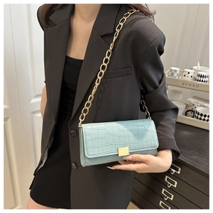 Détail d'un sac à main bleu clair à motif crocodile avec une chaîne dorée épaisse