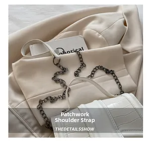 Detail of white crocodile embossed leather and elegant metal chain patchwork shoulder strap