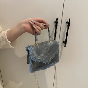 Blue denim crossbody bag with fringe trim and elegant gold chain strap detail