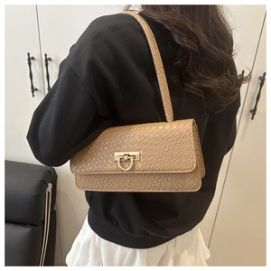 Detailed view of crocodile embossed shoulder bag with gold horsebit buckle on model
