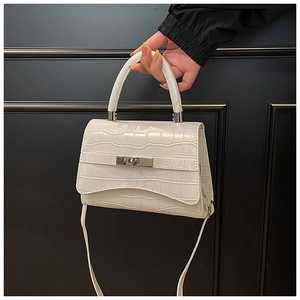 Close-up of white crocodile pattern handbag featuring a silver metallic twist lock