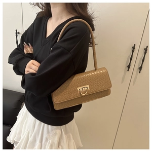 Detail of khaki brown woven shoulder bag with golden metallic clasp on model